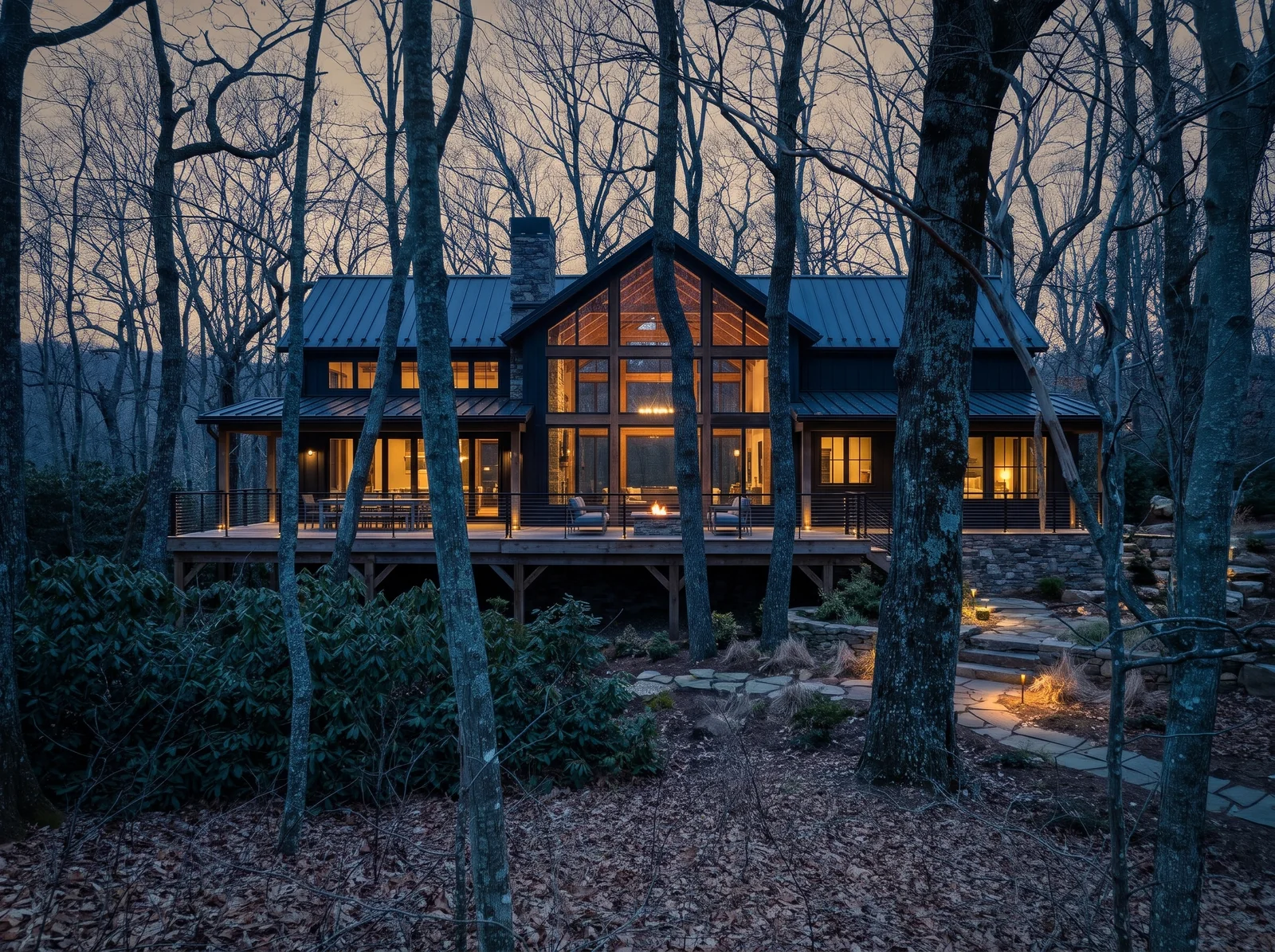 Concept rendering: the house at dusk with a lit two-story glass gable, a long deck with a fire table, rhododendron in front and oaks around it